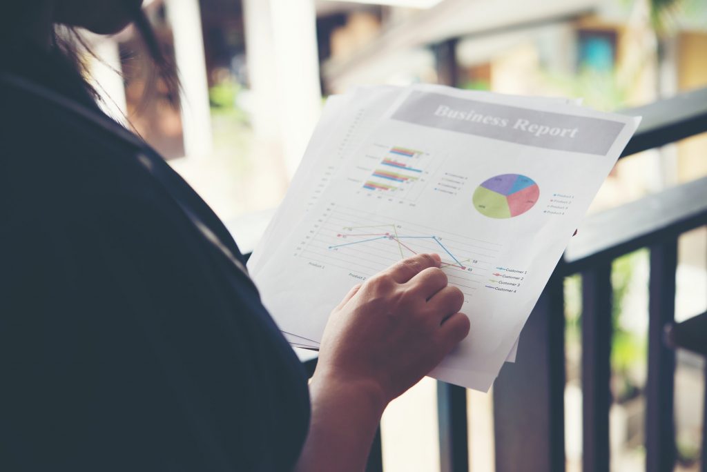 Hands of financial woman pointing on finance chart notes while working.